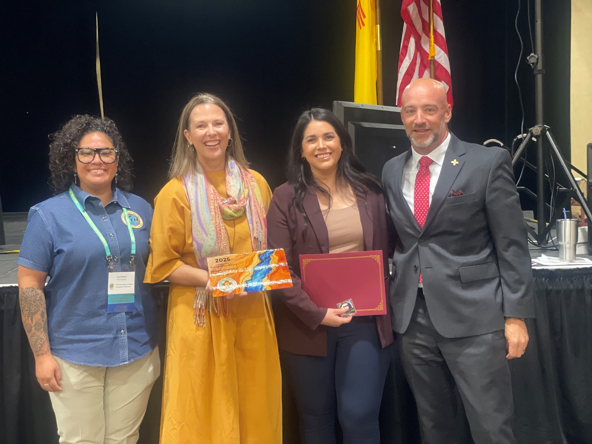 Joy V. Chavez, Dr. Terra V. Winter, Diana O’Brien and Thomas Walmsley stand together at the New Mexico Emergency Management Symposium holding the 2025 Special Recognition Award and a certificate.