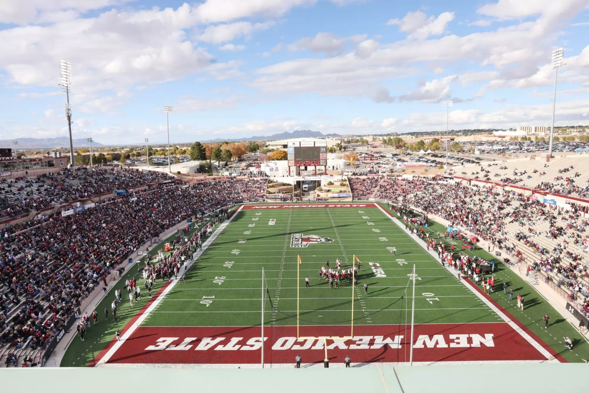 Aerial view of Aggie Memorial Stadium in Las Cruces during a New Mexico State football game, with fans filling the stands and the field set for kickoff.