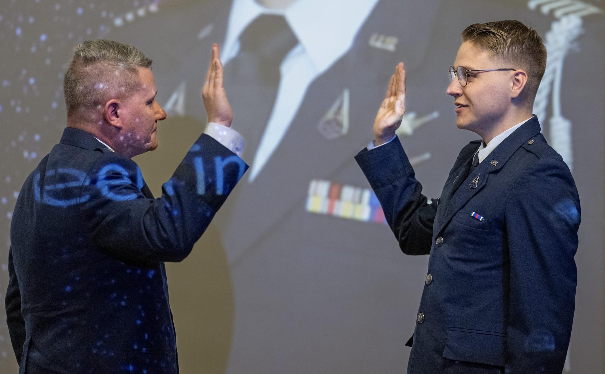 U.S. Air Force Brig. Gen. Lance French places his hand up as his son, in an Air Force uniform, raises his right hand during a commissioning ceremony into the U.S. Space Force.