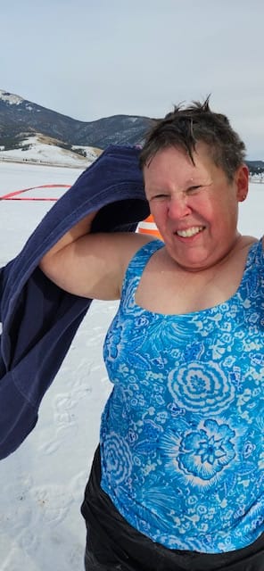 Gail Tate, wearing a blue swimsuit, wraps herself in a towel after completing a polar plunge at a New Mexico state park.