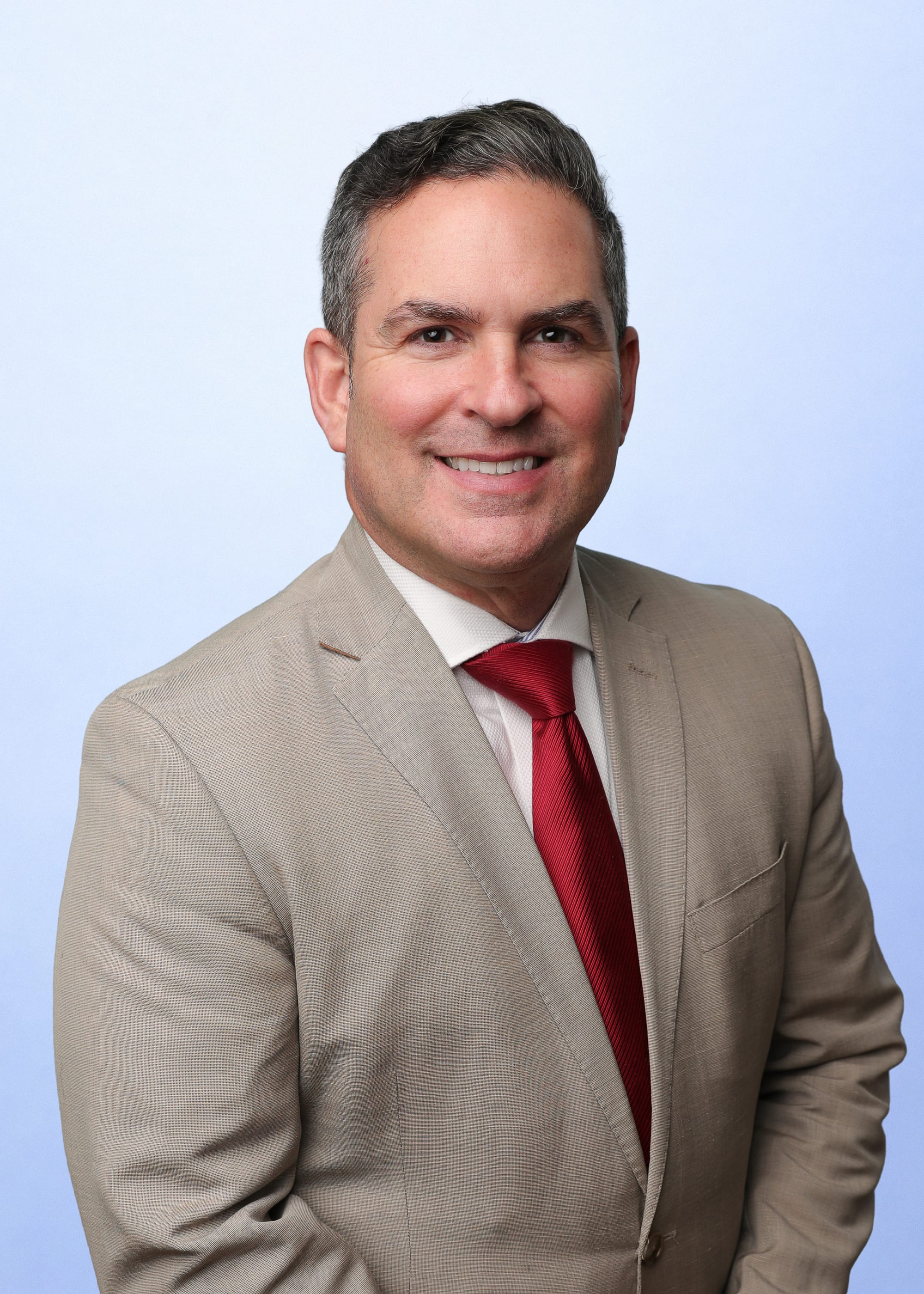 Patrick Shannon, chief executive officer of MountainView Regional Medical Center, poses for a professional headshot wearing a tan suit and red tie against a light background.