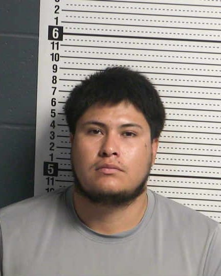 Booking photo of Axel Fabian Herrera Munoz against a height chart background.