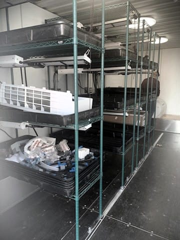 Shelving units with trays, lighting and irrigation equipment inside a container-based hydroponic plant-growing system developed by DACC and NMSU.