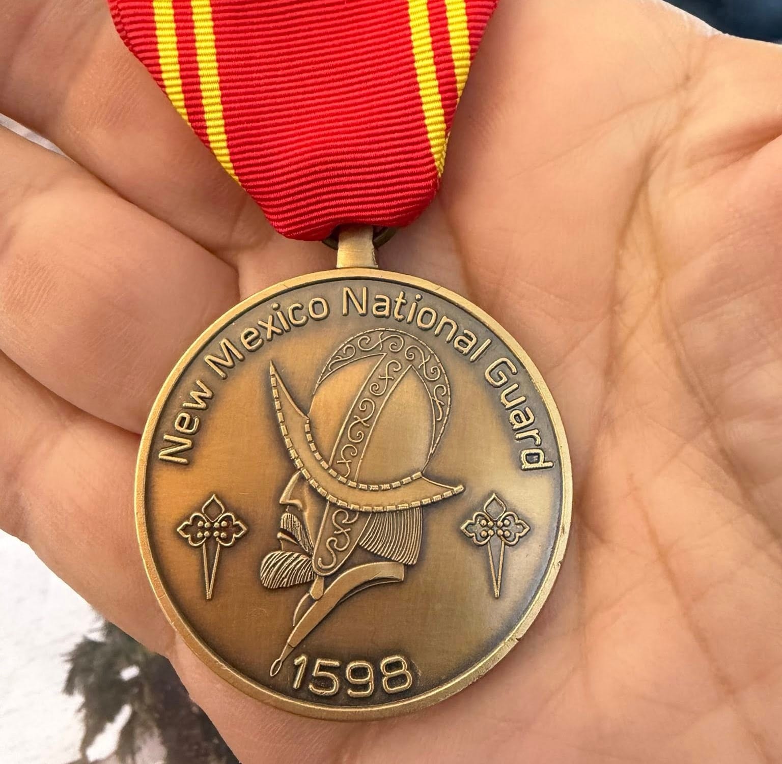 Close-up of the New Mexico National Guard Medal of Merit with red ribbon.
