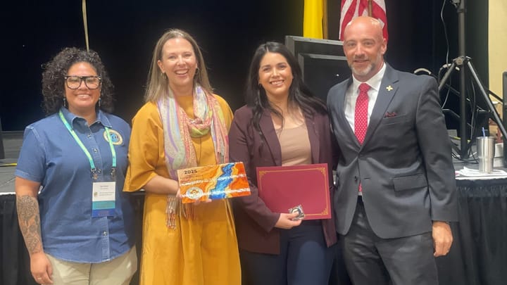Four people stand together at the New Mexico Emergency Management Symposium, holding the 2025 Special Recognition Award and a certificate during the presentation.