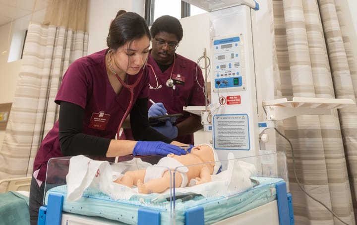 New Mexico State University nursing student Paola Martinez takes vitals on a lifelike infant simulator as fellow student Laron Harris observes in the renovated Skills and Simulation Center.