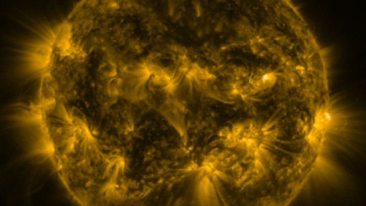 Close-up view of the sun in golden hues, showing intense solar activity and flares captured by a space telescope.