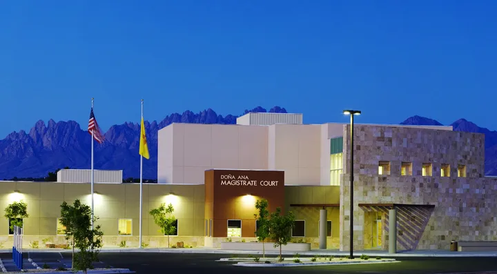 The Doña Ana Magistrate Court building in Las Cruces is pictured at dusk, with the Organ Mountains visible in the background.
