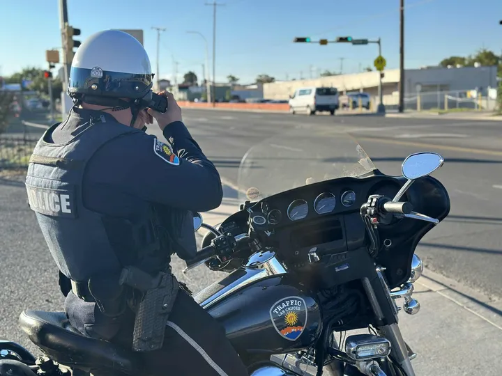 Las Cruces police traffic officer on a motorcycle uses a radar gun to monitor vehicles during a traffic enforcement operation on Solano Drive.