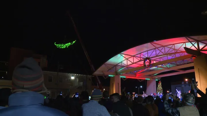 Crowd gathers in downtown Las Cruces as the illuminated chile pepper is raised before the annual Chile Drop on New Year’s Eve, with the stage lit in holiday colors.