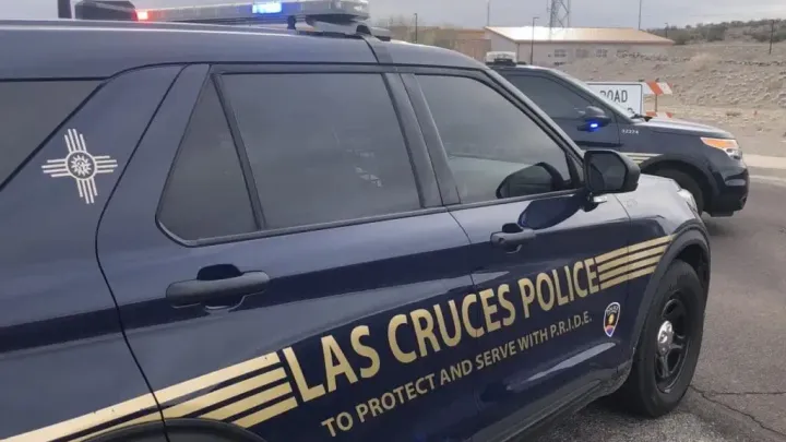 Two Las Cruces Police Department SUVs block a roadway with their emergency lights activated.