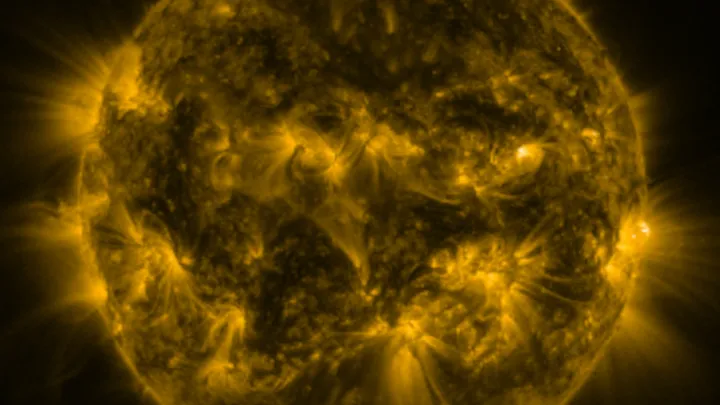 Close-up view of the sun in golden hues, showing intense solar activity and flares captured by a space telescope.