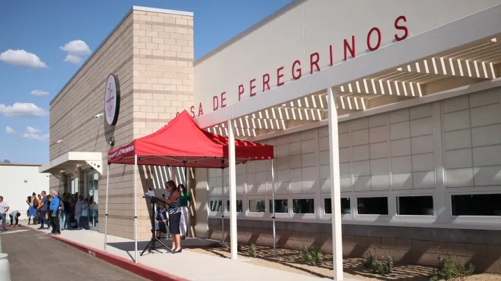 Casa de Peregrinos building in Las Cruces with red canopy tent outside as people line up near the entrance during a community event or distribution.