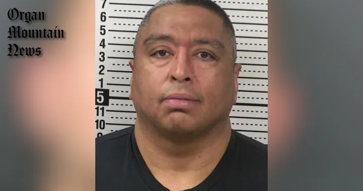 Former Las Cruces police officer Felipe Hernandez in a booking photo before a height chart, wearing a dark shirt.