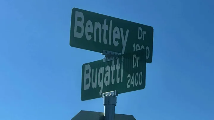 Street signs for Bentley Drive and Bugatti Drive are shown against a clear blue sky at the intersection where Las Cruces police responded to a fatal shooting at a house party.