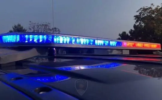 A Las Cruces Police Department patrol vehicle with its blue and red emergency lights activated during dusk.