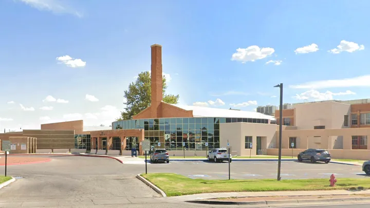 Exterior of the Third Judicial District Court in Las Cruces, New Mexico, showing the main entrance and a tall brick chimney on the court complex.