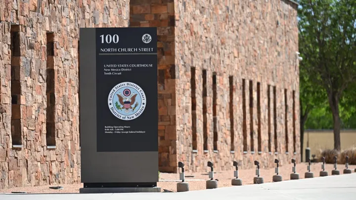 Exterior view of the United States Courthouse in Las Cruces, showing a sign reading “100 North Church Street” and the seal of the U.S. District Court for the District of New Mexico.