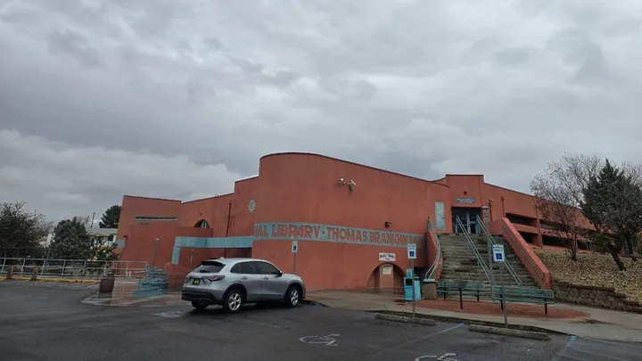 Exterior of the Thomas Branigan Memorial Library in Las Cruces under overcast skies, with the main entrance, steps and parking area visible.