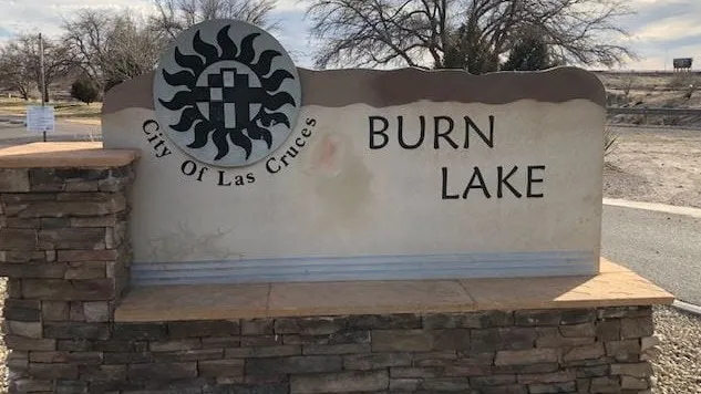 Sign at the entrance to Burn Lake in Las Cruces, with the City of Las Cruces emblem displayed beside the site name.