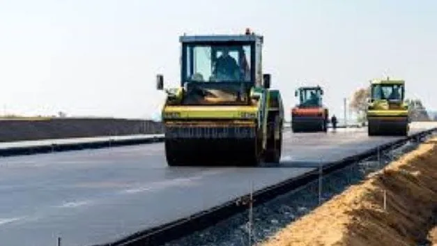 Road construction crews use heavy rollers to apply surface treatment during a pavement maintenance project.