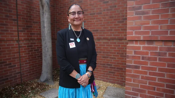 Wilhelmina Yazzie, lead plaintiff in the Yazzie/Martinez education lawsuit, stands outdoors in front of a brick building.