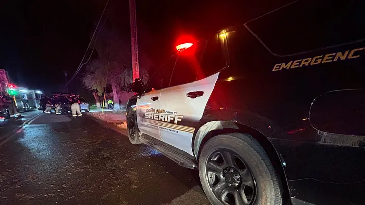 Doña Ana County Sheriff’s Office patrol unit with emergency lights activated at a nighttime response scene, with responders and vehicles visible along the roadside.