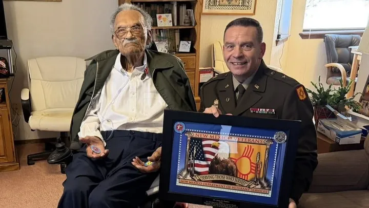 James C. Flowers sits in his Las Cruces home as a New Mexico veterans official presents him with a framed award recognizing his service as a Tuskegee Airman.