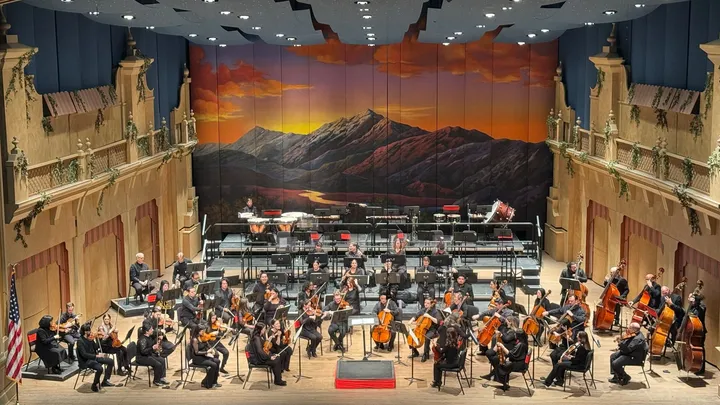 The El Paso Symphony Orchestra performs onstage beneath a painted mountain sunset backdrop during “The Seventh Symphonies: Classical Poetry” concert.