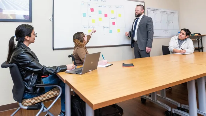 Small group meeting at NMSU’s Arrowhead Center with participants discussing ideas on a whiteboard during a business planning session