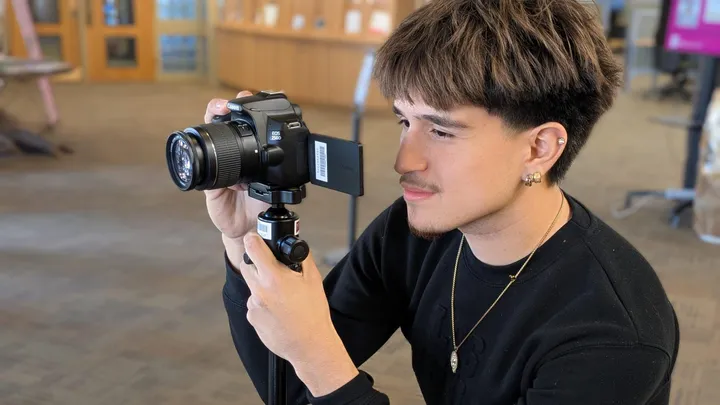 NMSU student using a camera mounted on a small tripod inside the university library as part of the library’s Loanable Technology Program.