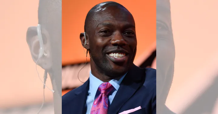 Terrell Owens smiles while wearing a suit and tie during a public appearance.
