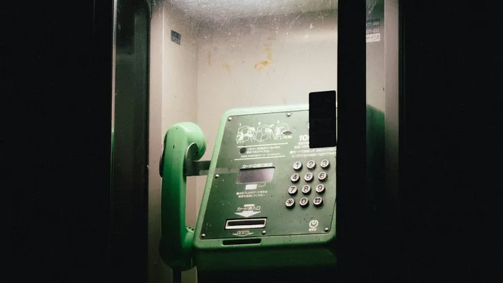 Inmate telephone inside a prison booth with keypad and receiver visible