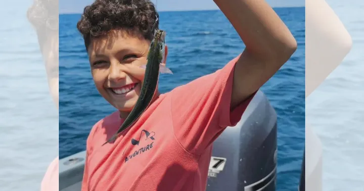 Undated photo of Chris holding a fish on a boat with open water in the background.